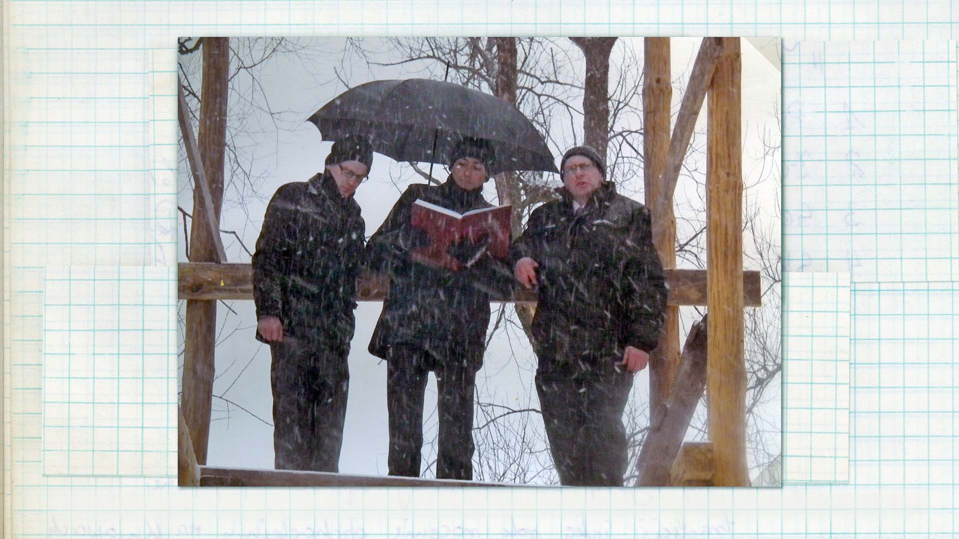 Wygłaszanie przywołówek, Niedziela Wielkanocna, 2013 Fotografia kolorowa. Trzech mężczyzn stoi na podeście drewnianej konstrukcji. Jeden z nich trzyma w swoich dłoniach księgę w czerwonej oprawie, drugi natomiast trzyma czarny parasol. Intensywnie pada obfity śnieg.